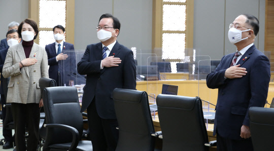 김부겸 국무총리와 유은혜 부총리 겸 교육부장관(왼쪽), 홍남기 경제부총리 겸 기획재정부 장관(오른쪽) 등 국무위원들이 28일 오전 세종시 정부세종청사에서 서울과 영상으로 연결해 열린 국무회의에서 국기에 경례하고 있다. <연합뉴스>